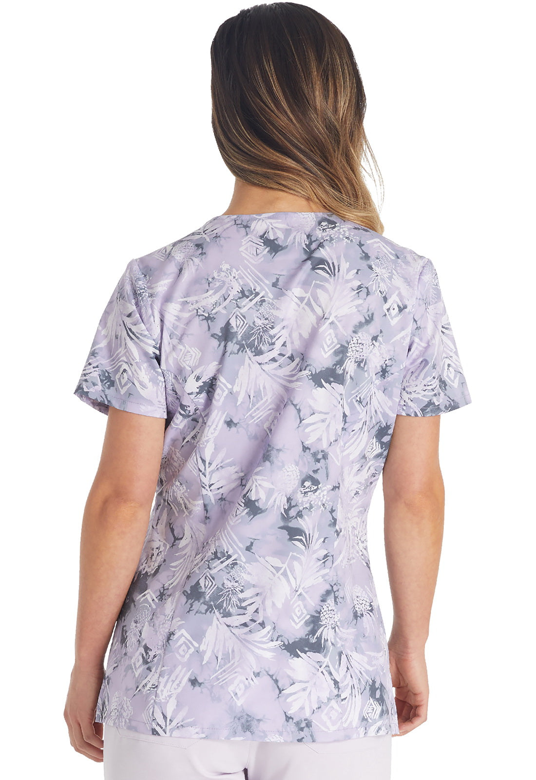 Woman wearing Tropic Distress V-Neck Scrub Top in lavender tropical floral print for medical professionals