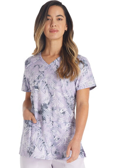 Woman wearing Tropic Distress V-Neck Scrub Top in lavender tropical floral print for medical professionals